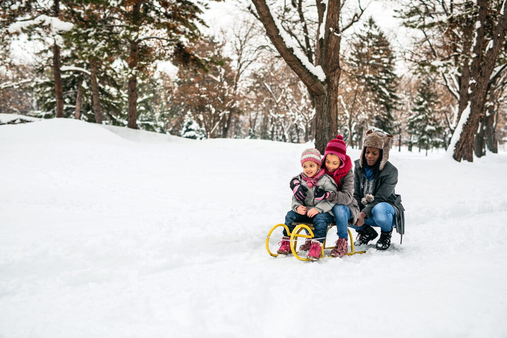 Single mom sledging with kids in public park
